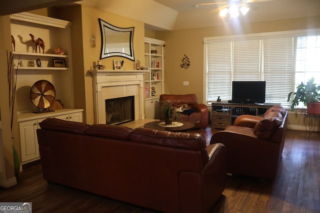 living room with dark wood-type flooring, built in shelves, and ceiling fan