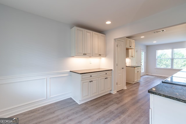 kitchen featuring white cabinetry, dark stone counters, and light hardwood / wood-style flooring