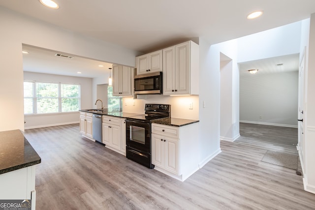 kitchen with stainless steel appliances, light wood-type flooring, dark stone counters, and white cabinets