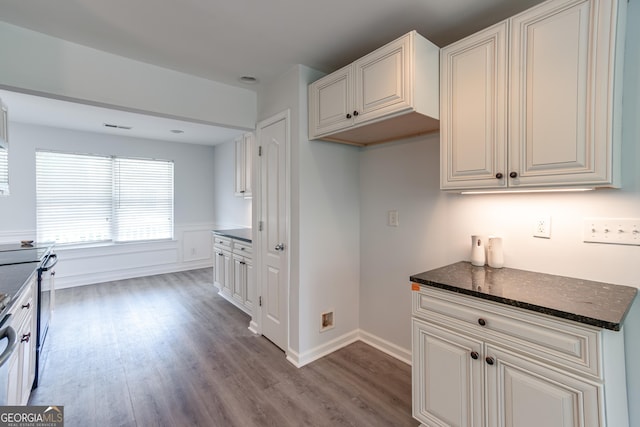 kitchen with white cabinetry, dark stone counters, light hardwood / wood-style floors, and electric stove