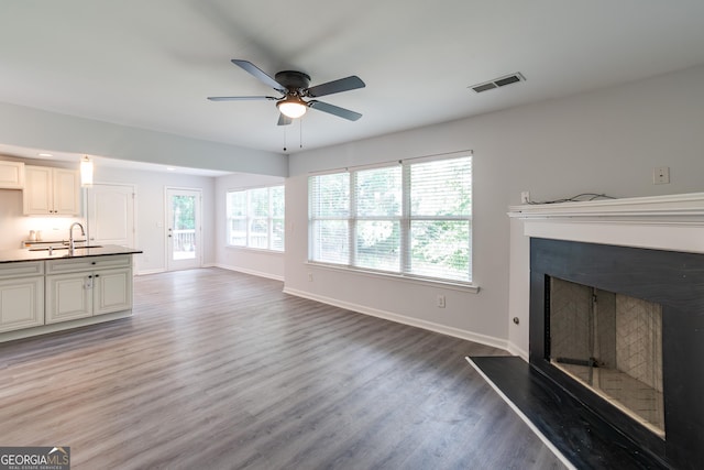 unfurnished living room featuring wood-type flooring, sink, and ceiling fan