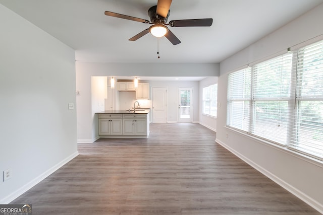 unfurnished living room with sink, wood-type flooring, and ceiling fan