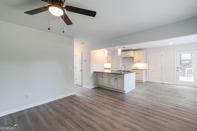 unfurnished living room featuring ceiling fan, sink, and light hardwood / wood-style flooring