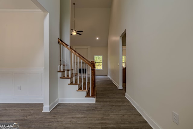 stairway with ornamental molding, hardwood / wood-style flooring, a high ceiling, and ceiling fan