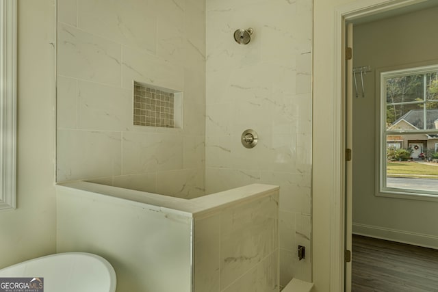 bathroom with hardwood / wood-style floors and a tile shower