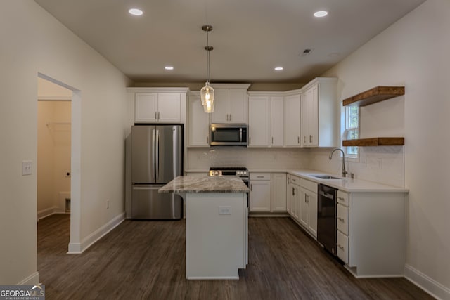 kitchen with dark wood-type flooring, stainless steel appliances, a center island, decorative light fixtures, and white cabinets