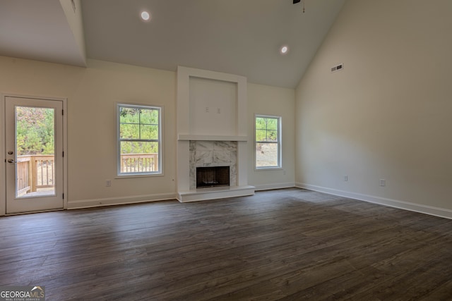 unfurnished living room featuring dark hardwood / wood-style flooring, a high end fireplace, high vaulted ceiling, and a wealth of natural light