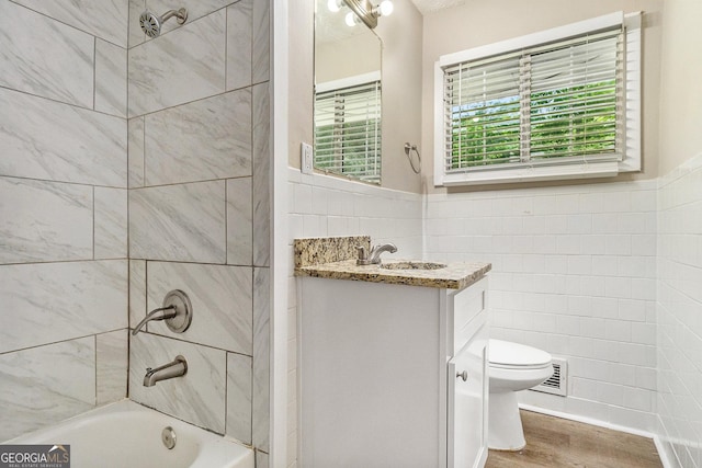 full bathroom with tile walls, hardwood / wood-style flooring, vanity, and toilet