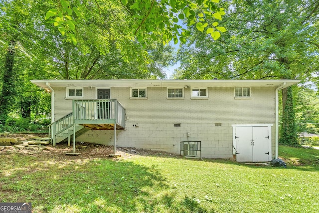 rear view of property featuring a wooden deck and a lawn