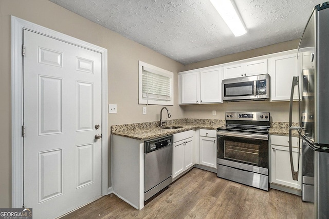 kitchen featuring white cabinets, appliances with stainless steel finishes, sink, and hardwood / wood-style flooring