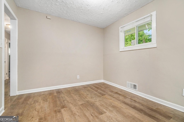 spare room with a textured ceiling and wood-type flooring