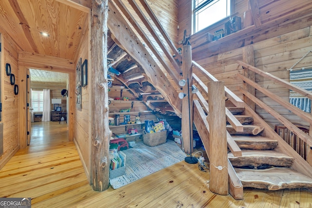 stairs featuring wooden walls, hardwood / wood-style floors, and wood ceiling