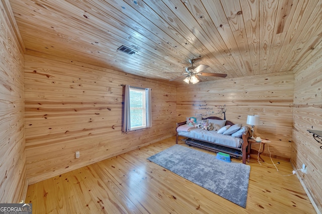 bedroom with wood walls, wooden ceiling, and light hardwood / wood-style flooring