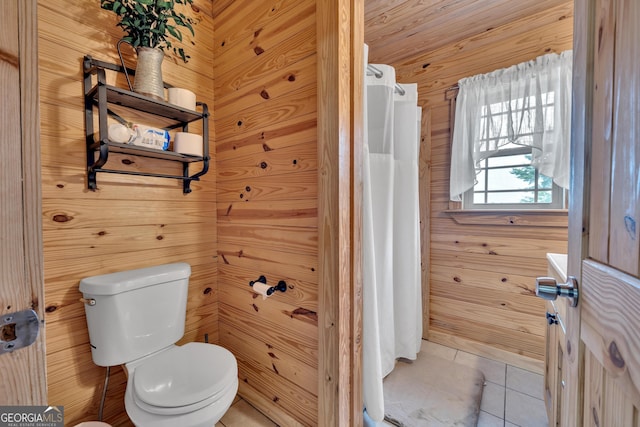 bathroom with tile patterned flooring, toilet, and wooden walls