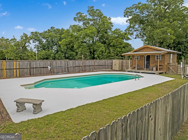 view of swimming pool with a yard, a deck, and an outdoor structure