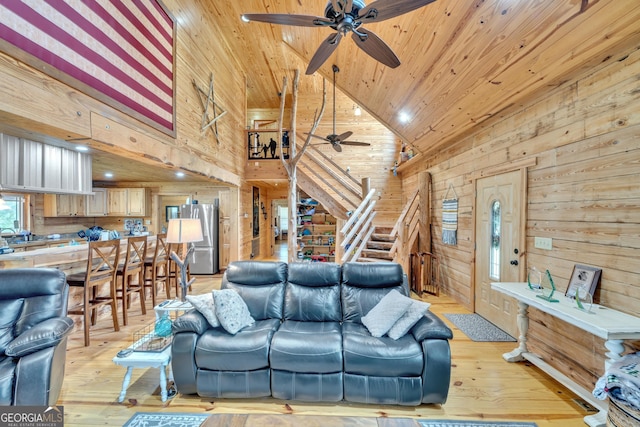 living room with ceiling fan, wooden ceiling, high vaulted ceiling, wood walls, and light wood-type flooring