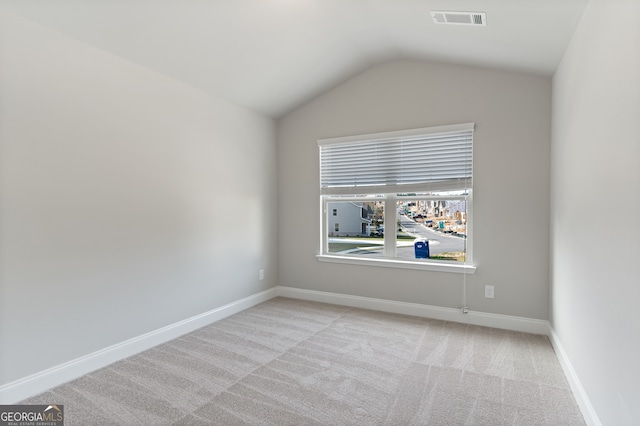 unfurnished room with lofted ceiling and light colored carpet