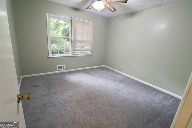 carpeted empty room with ceiling fan and a textured ceiling