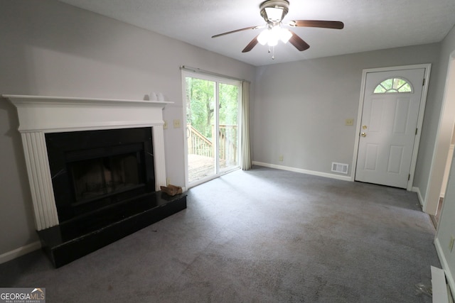 unfurnished living room with ceiling fan, a healthy amount of sunlight, and dark carpet