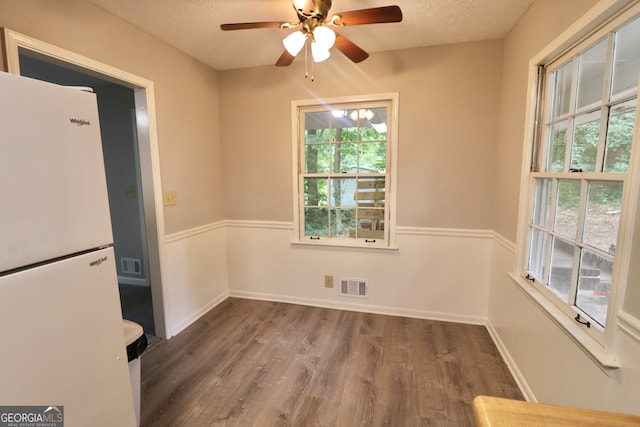 unfurnished dining area with a textured ceiling, wood-type flooring, and ceiling fan