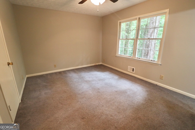 unfurnished room with dark colored carpet, ceiling fan, and a textured ceiling