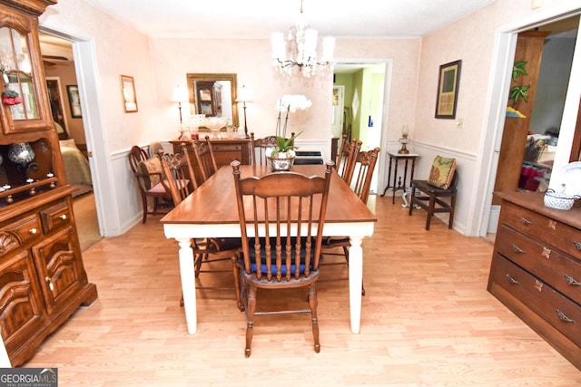 dining room featuring light wood-style flooring, wainscoting, and a chandelier