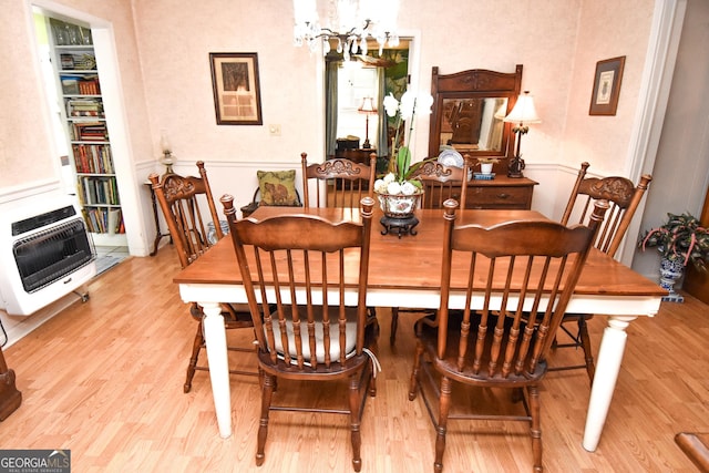 dining space featuring heating unit, wood finished floors, and a chandelier