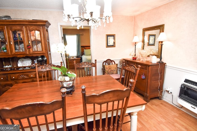 dining space featuring heating unit, a chandelier, light wood-style flooring, and ornamental molding