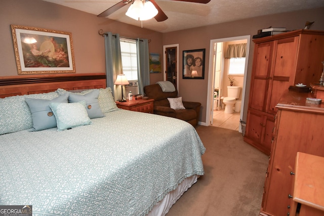 bedroom with light colored carpet, ensuite bathroom, and a ceiling fan