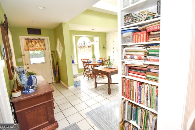 hallway with light tile patterned flooring, a notable chandelier, baseboards, and a wealth of natural light