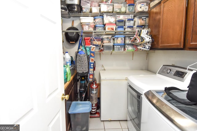 washroom with cabinet space, light tile patterned flooring, and washer and clothes dryer