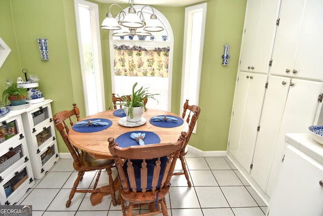 dining space featuring light tile patterned floors, a notable chandelier, and baseboards