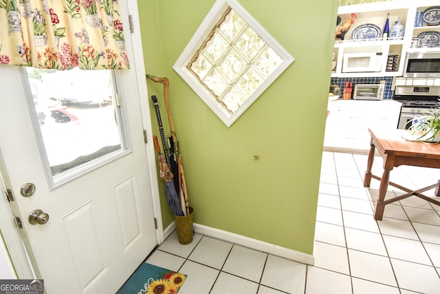 entryway with a toaster, light tile patterned floors, and baseboards