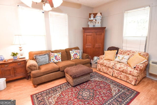 living area featuring an AC wall unit, a ceiling fan, and light wood-style floors