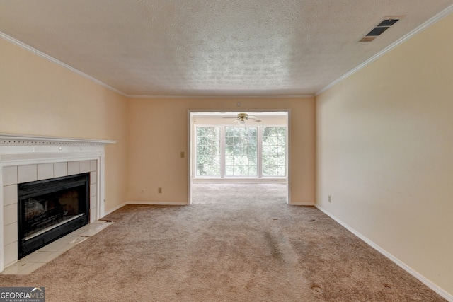 unfurnished living room with a tiled fireplace, light carpet, crown molding, and ceiling fan