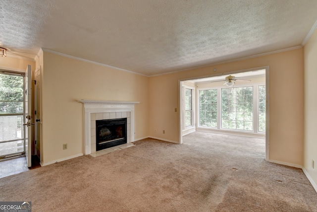 unfurnished living room with a tiled fireplace, ceiling fan, light colored carpet, and ornamental molding