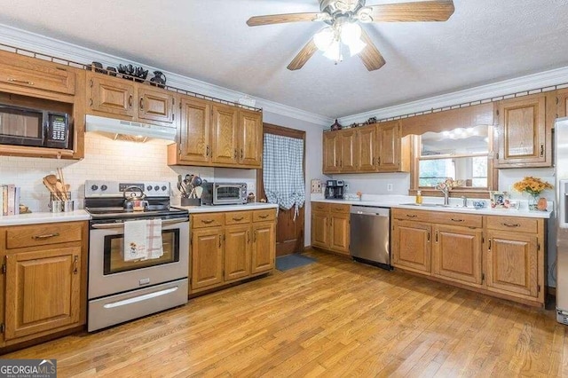 kitchen featuring sink, light wood-type flooring, ornamental molding, appliances with stainless steel finishes, and backsplash