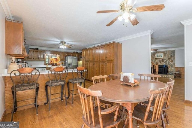 dining area with ceiling fan, ornamental molding, light hardwood / wood-style flooring, and a textured ceiling