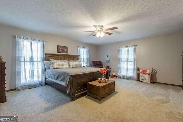 bedroom with ceiling fan, carpet floors, and a textured ceiling