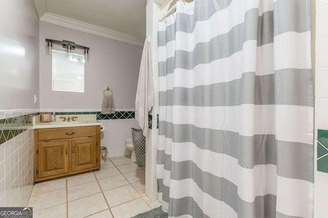 bathroom with crown molding, tile walls, vanity, tile patterned floors, and toilet