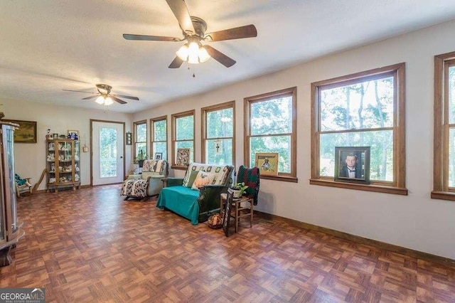 living area with dark parquet flooring, a textured ceiling, and ceiling fan