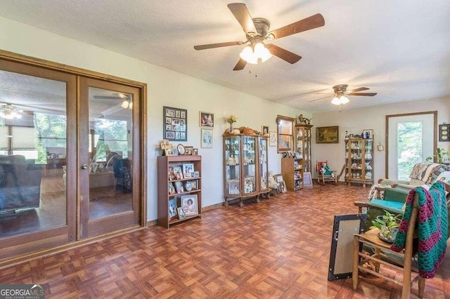 living area featuring ceiling fan, a textured ceiling, dark parquet floors, and french doors