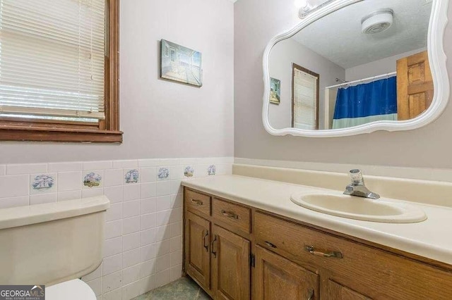 bathroom featuring vanity, tile walls, and toilet