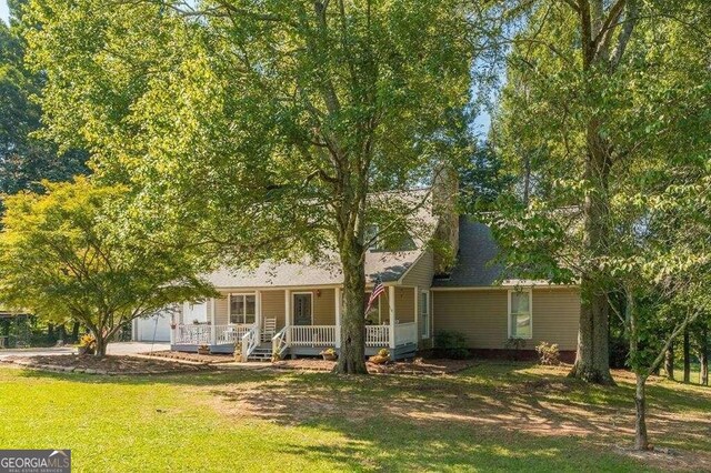 rear view of property featuring covered porch and a lawn