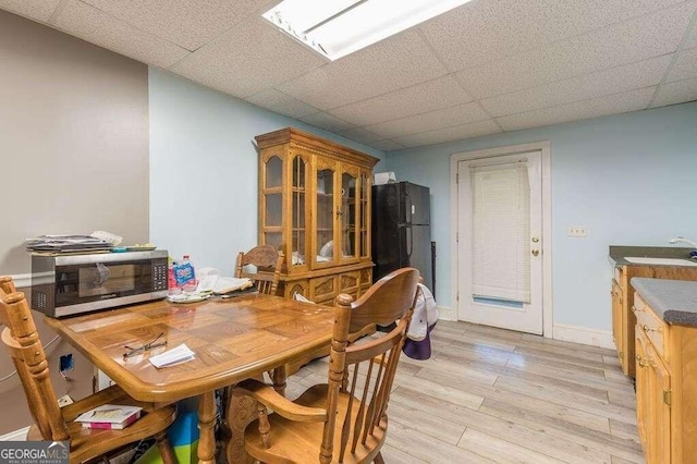 dining area with sink, light hardwood / wood-style flooring, and a paneled ceiling