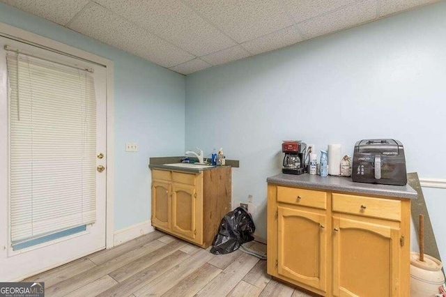 kitchen featuring sink, a paneled ceiling, and light hardwood / wood-style floors