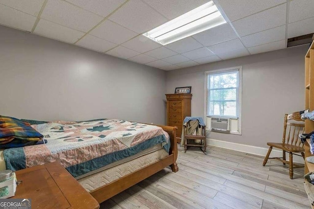 bedroom with light hardwood / wood-style flooring, cooling unit, and a paneled ceiling