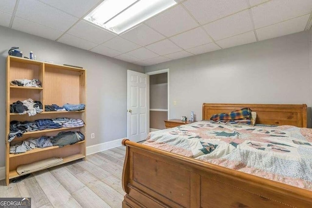 bedroom with a paneled ceiling and light wood-type flooring