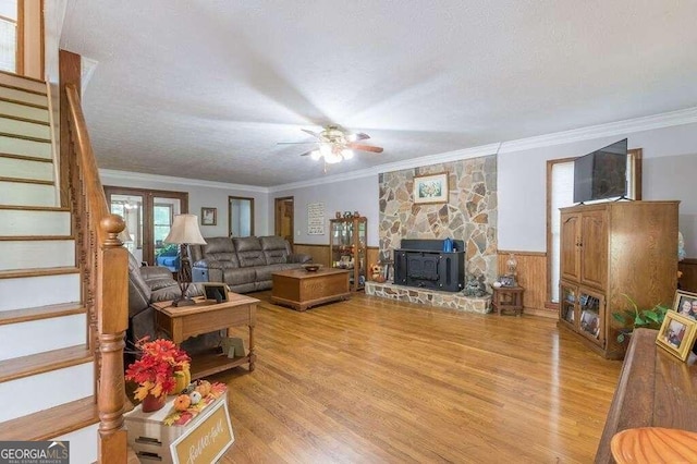 living room featuring ornamental molding, light hardwood / wood-style floors, ceiling fan, and a wood stove