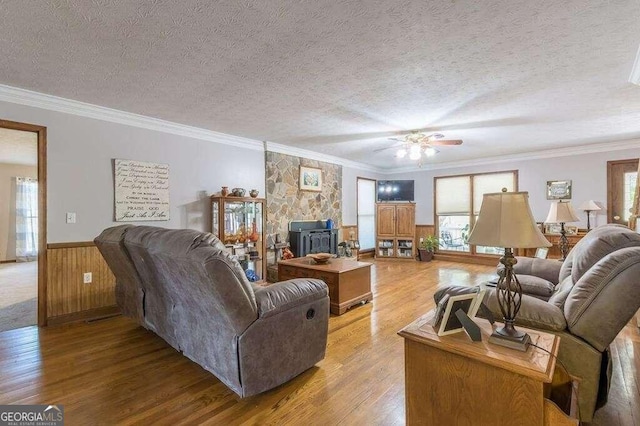 living room featuring crown molding, ceiling fan, a textured ceiling, and light wood-type flooring